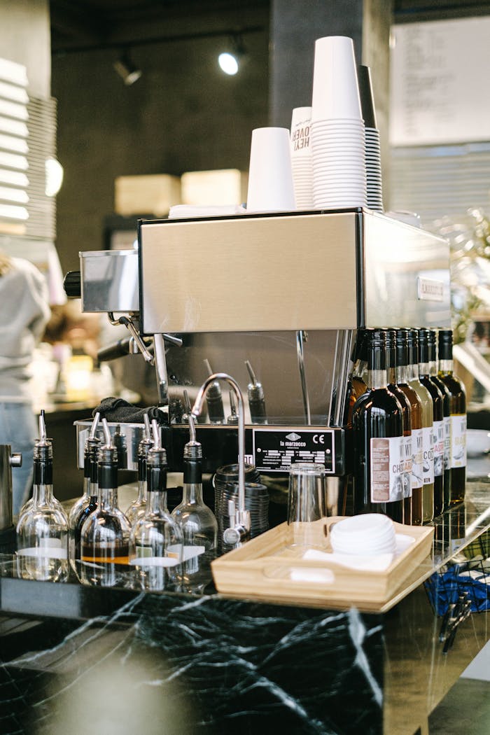 Close-up of a modern espresso machine with syrups at a coffee shop counter.